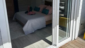 Un dormitorio con cama, almohadas y puerta corrediza de vidrio que da a un balcón.