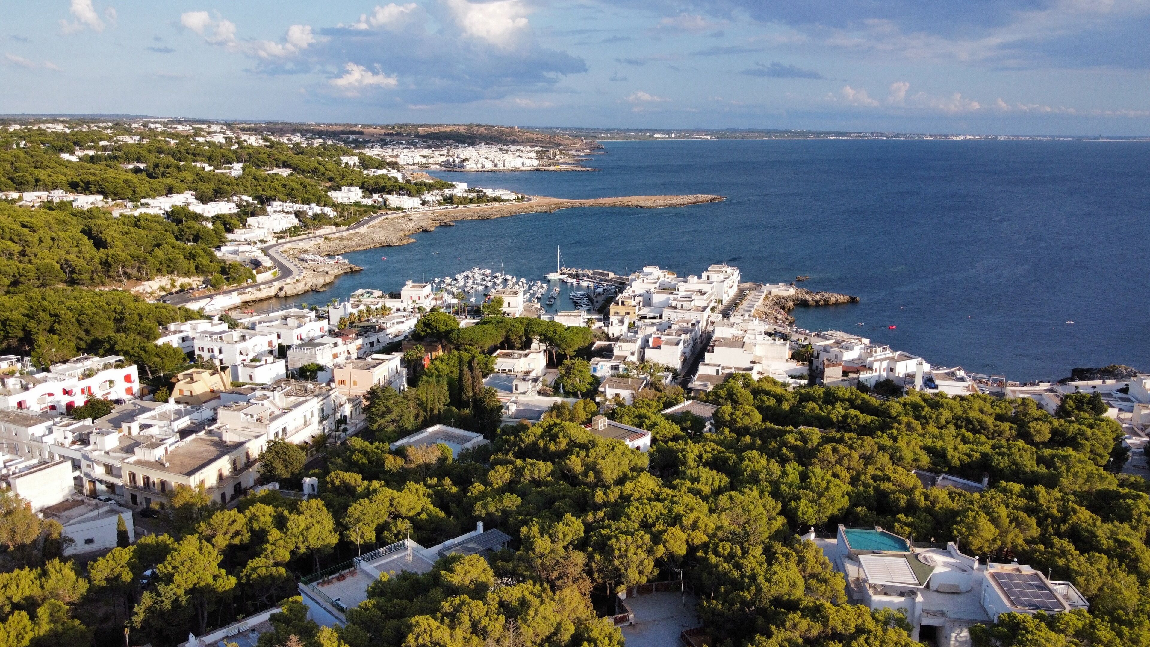 A coastal town with white buildings, a marina, and a view of the sea.