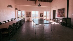 Une pièce spacieuse équipée d’une table de ping-pong, de plusieurs chaises, d’une table à manger et ornée d’œuvres d’art sur les murs.
