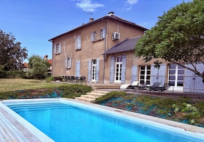 A two-story building with a swimming pool, outdoor seating, and a covered area with chairs. - "The Old School" in an authentic southern French village, with high ceilings both inside and out (Salclas)