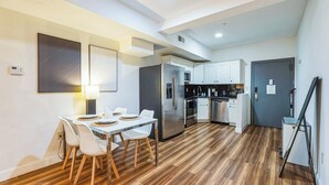 A modern kitchen with white cabinets, stainless steel appliances, and a dining area with a white table and chairs. - Elegant 2-bedroom apartment near Philadelphia Convention Center & Reading Market (Philadelphia)