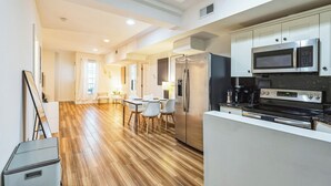 A modern kitchen with stainless steel appliances, a dining area with a wooden floor, and white cabinetry. - Elegant 2-bedroom apartment near Philadelphia Convention Center & Reading Market (Philadelphia)