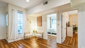A spacious room with hardwood flooring, a small round table with chairs, a lamp, and a bed in the background. - Elegant 2-bedroom apartment near Philadelphia Convention Center & Reading Market (Philadelphia)