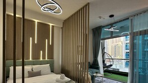 Een moderne slaapkamer met een groot bed, een hangstoel en uitzicht op de stad.
