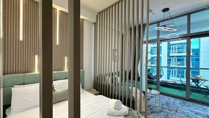 Een hotelkamer met twee bedden, uitzicht op de stad en een balkon met buitenmeubilair.