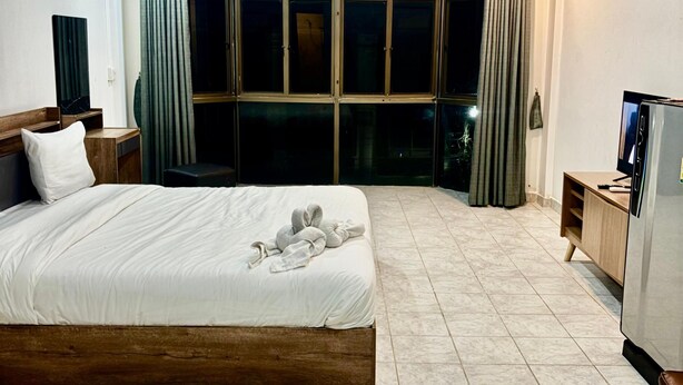 Une chambre d’hôtel avec un grand lit, une télévision, la climatisation et une vue sur l’extérieur par une fenêtre munie de rideaux.