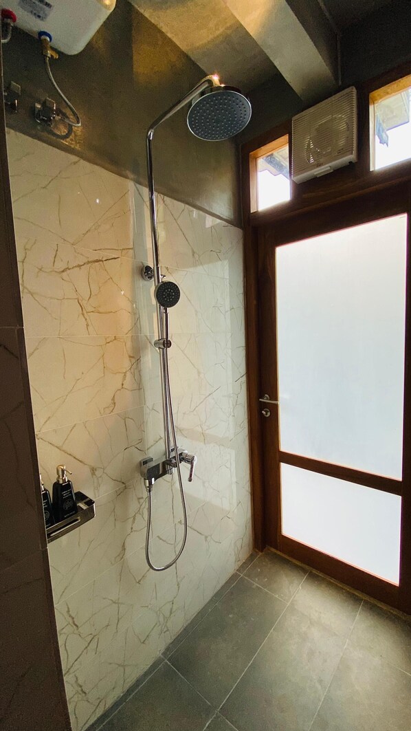 Un baño con ducha, paredes de mármol y una puerta de madera.