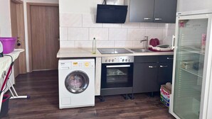 A compact kitchen with a washing machine, a stove, and a refrigerator. - Apartment in Danma mit Gemeinschaftskuche (Laubach)