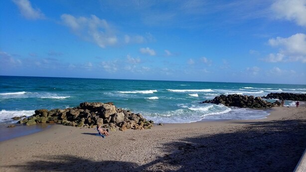 Una playa con formaciones rocosas y olas.