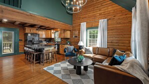 A spacious living area with a wooden floor, a round coffee table, a sofa, and a dining table with chairs.