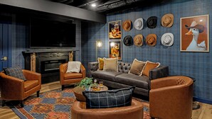 A cozy living room with leather sofas, a fireplace, and a wall decorated with hats.