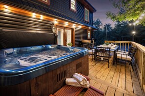 A wooden deck with a hot tub, outdoor seating, and a wooden house in the background. - Bourbon Country Cabin- Game Room, Fire Pit, and Hot Tub (Bardstown)