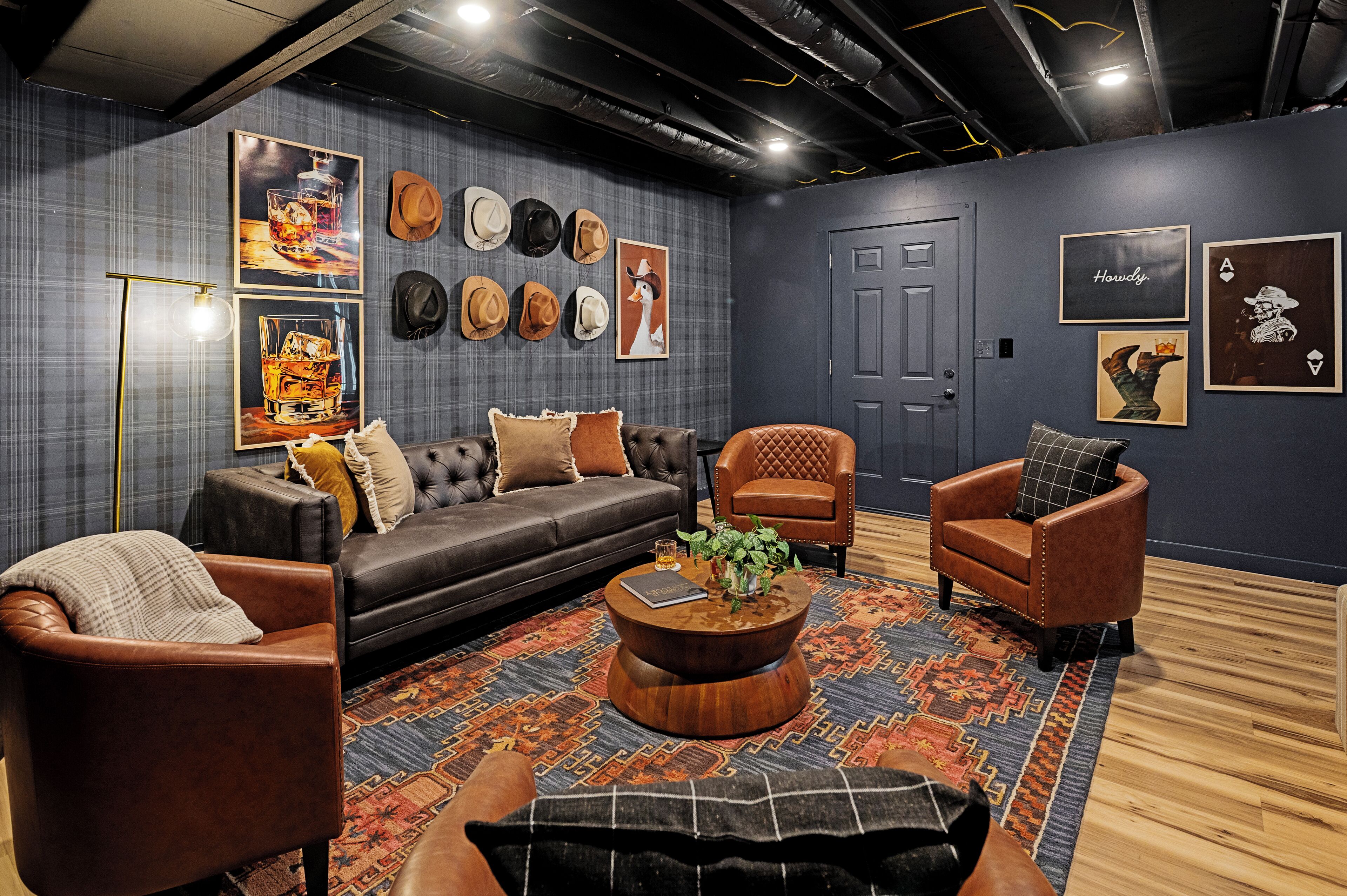 A modern living room with a dark grey wall, a patterned rug, leather sofas, and a coffee table.