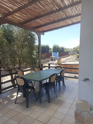 Un patio al aire libre con zona cubierta, una mesa y sillas.