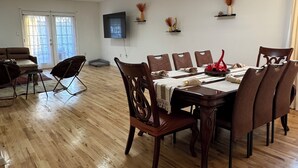 A spacious dining area with wooden flooring, a dining table set with chairs, and a television mounted on the wall. - Cityscape Retreat In Jersey City. Spacious apt for short and long term stay. (Jersey City)