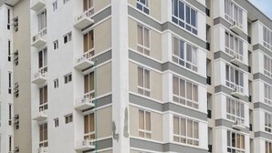 Un edifici residencial de diverses plantes amb balcons, una zona d'aparcament i un camí pavimentat.