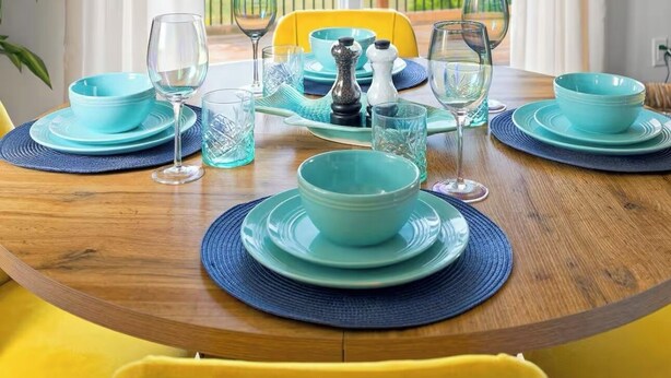 A dining table set with blue and green plates, glasses, and a salt and pepper set. A yellow chair is positioned at the table. - Waterview Retreat| Large Deck | Minutes to Downtown  (Charlottetown)