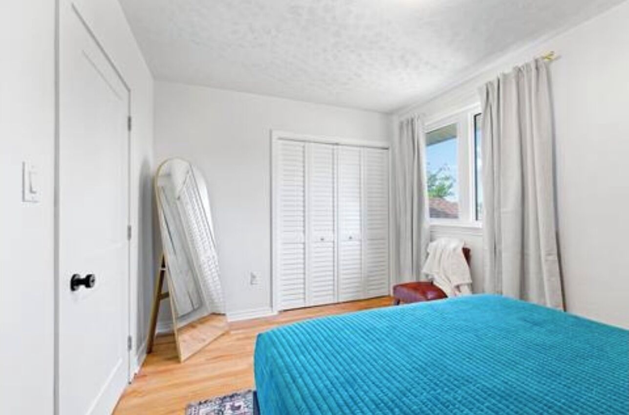 Un dormitorio con cama, armario, ventana con cortinas y puerta.