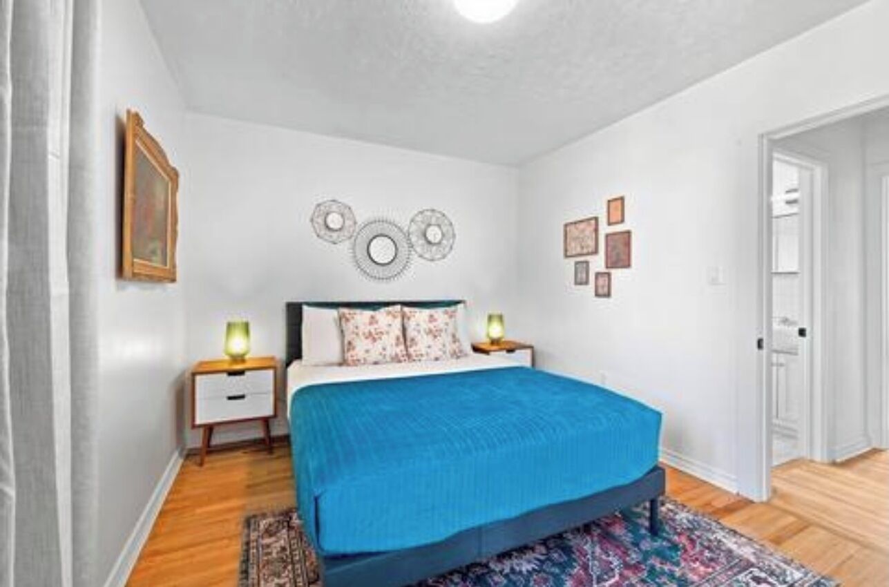 A bedroom with a bed, bedside tables, a rug, and wall decor.