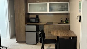 Una cocina moderna con zona de comedor, que incluye un ventilador de techo, un microondas, un refrigerador y una mesa de comedor de madera con sillas.