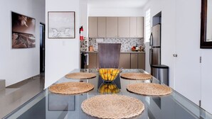 A modern kitchen with a glass dining table, woven placemats, and a fruit bowl. - Dream House on Isla Verde Beach + Terrace (Carolina)