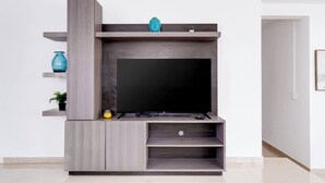 A modern entertainment unit with a flat-screen TV, wooden shelves, and a small Buddha statue. - Dream House on Isla Verde Beach + Terrace (Carolina)