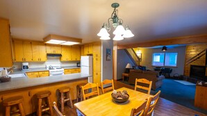 A kitchen with wooden cabinets, a dining table with chairs, and a chandelier. - Cabins at Strawberry - Fir (Strawberry)