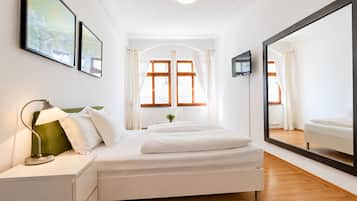 Un dormitorio con cama, mesita de noche, lámpara y un espejo grande.