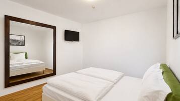 A bedroom with a bed, a mirror, a television, and a framed picture on the wall.