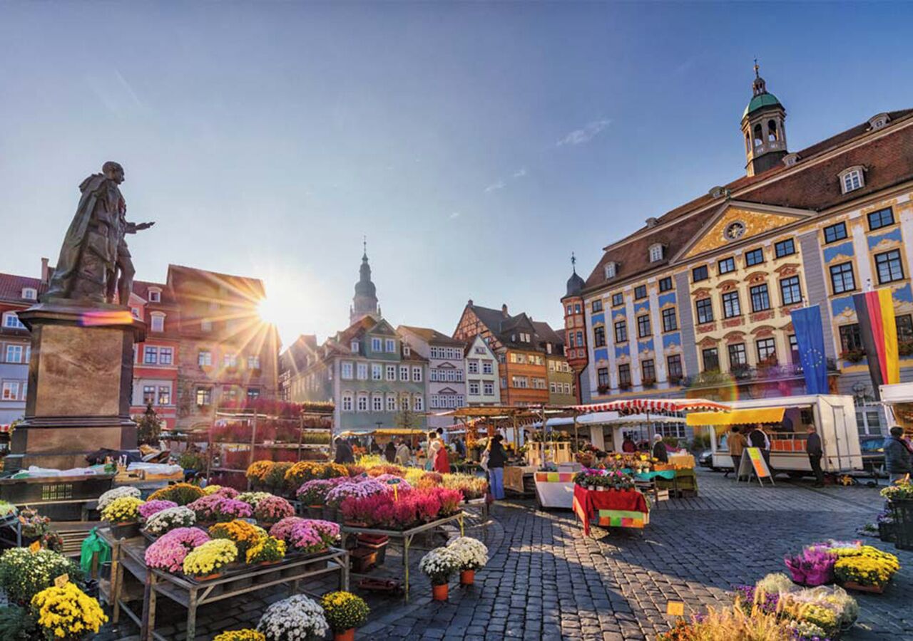 A historic square with cobblestone pavement, a statue, and colorful buildings.