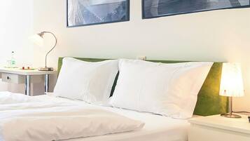 Ein Hotelzimmer mit einem Bett, Nachttischen, einer Lampe und zwei gerahmten Bildern an der Wand.
