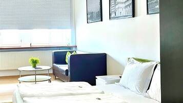 Una camera d'albergo con un letto, una sedia, un tavolino e tre quadri appesi al muro.