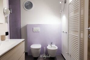 Et badeværelse med toilet, bidet og et spejl.