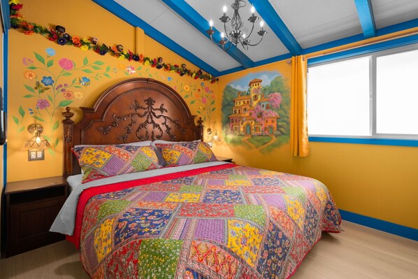 A bedroom with a wooden bed, colorful floral wall art, and a mural of a building. - Enchanted Dreams: Theater, Arcades, Playground + (Garden Grove)