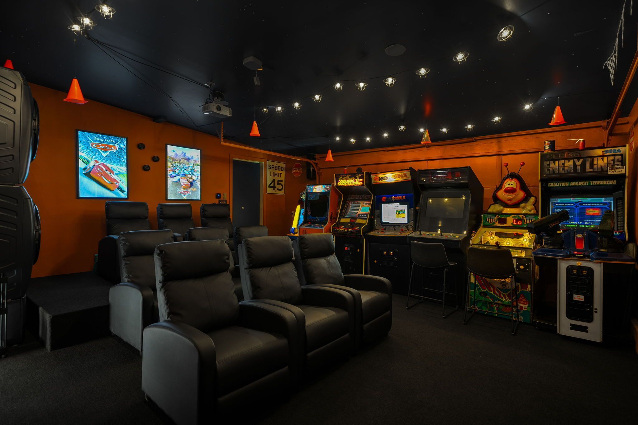 A gaming room with multiple arcade machines, comfortable seating, and a speed limit sign.