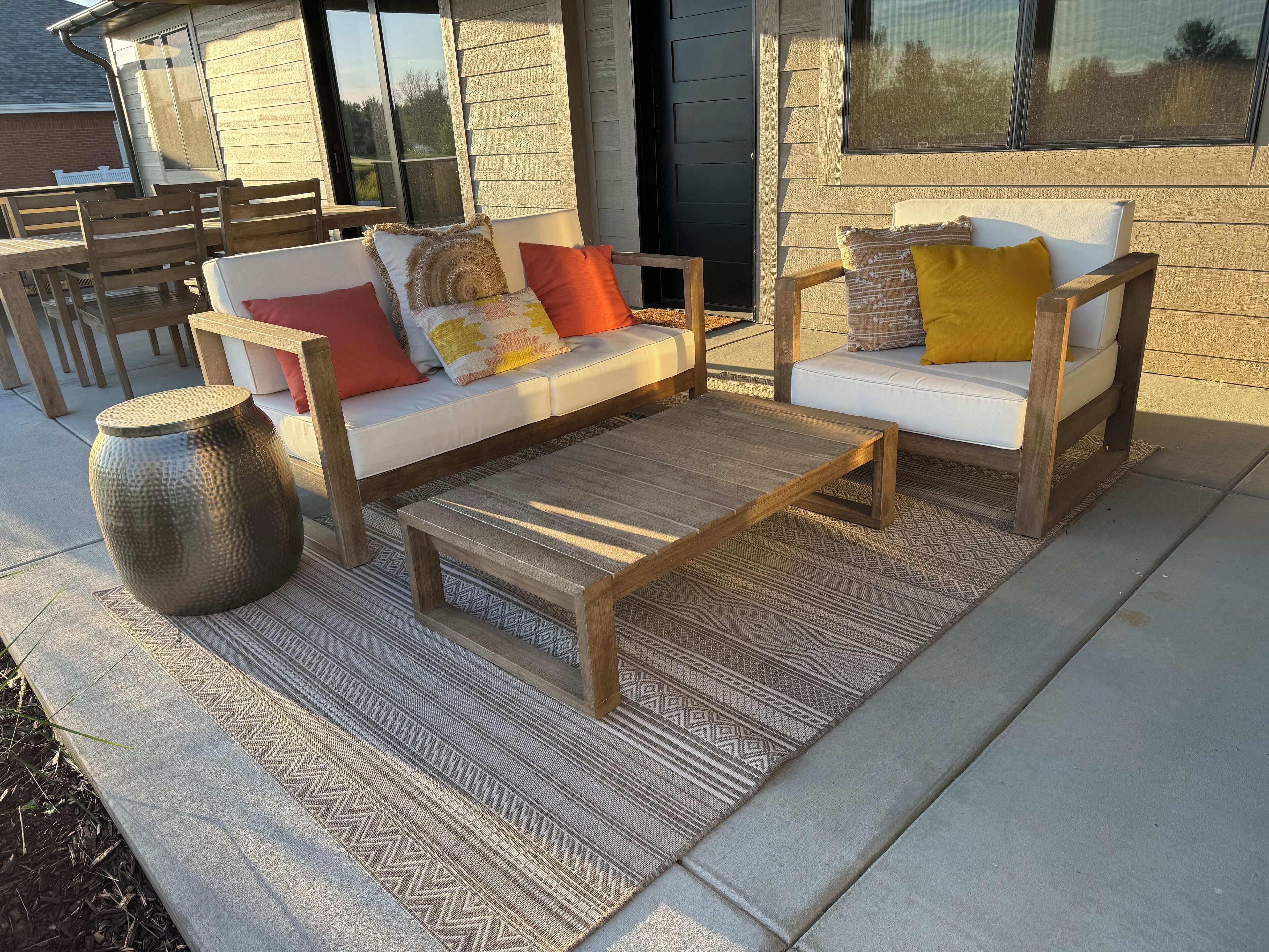 Un patio con dos sofás blancos, una mesa de centro de madera y un jarrón grande.