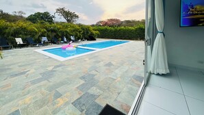 A swimming pool with lounge chairs and a pink flamingo float. - Kai Guana House (Provincia de Guanacaste)