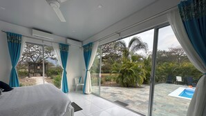 A bedroom with a large bed, a sliding glass door to a pool area, and a view of the outdoors. - Kai Guana House (Provincia de Guanacaste)