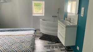 A modern bathroom with a freestanding bathtub, a vanity with a mirror, and a window providing natural light. - Provencal-style gîte in a quiet location, private pool, view of the Ardèche in the Drôme. (Albon)