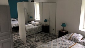 A bedroom with a mirrored wardrobe, a bed with patterned bedding, and two bedside lamps. - Provencal-style gîte in a quiet location, private pool, view of the Ardèche in the Drôme. (Albon)