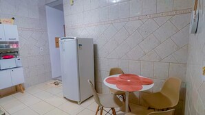A compact kitchen with a refrigerator, a microwave, and a dining area with chairs and a table. - Cozy house in front of Maria. (Aparecida)