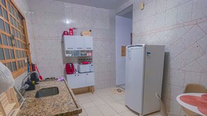 A compact kitchen with a sink, countertop, and a refrigerator. - Cozy house in front of Maria. (Aparecida)