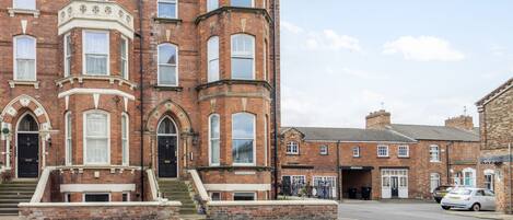 A historic building with a prominent corner turret, large windows, and a brick facade.
