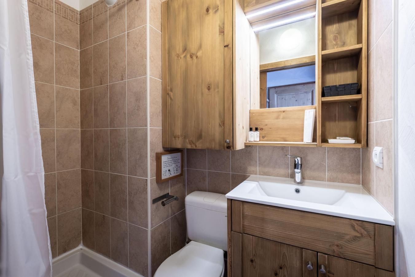 Ein Badezimmer mit Dusche, Toilette und Holzschränken.
