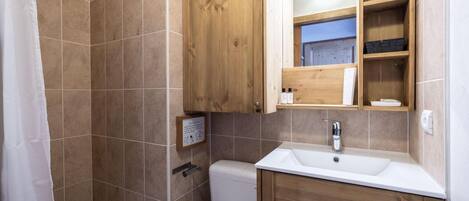 Ein Badezimmer mit Dusche, Toilette und Holzschränken.