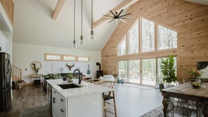 Una cocina amplia con una isla grande, vigas de madera en el techo y ventanas amplias.