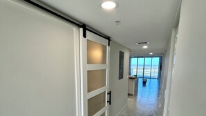 A hallway with a sliding door, marble flooring, and a view to a balcony. - Newly, renovated, modern, OCEANFRONT 2 bedroom, 2 bathroom with 25 ft balcony (Port Orange)