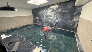 Et værelse med en stor, klar swimmingpool, en loftlampe og en væg med et marmorlignende mønster.