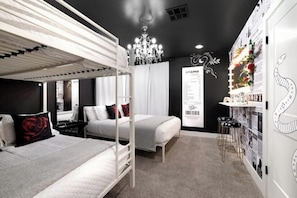 Un dormitorio moderno con literas, un candelabro, un tocador con espejo y una pared con elementos decorativos.