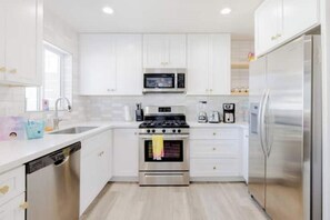 A modern kitchen with white cabinets, stainless steel appliances, and a dishwasher.